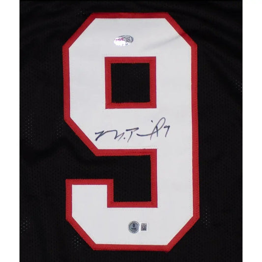 Black sports jersey with a white number ’9’’ outlined in red, signed by an athlete.