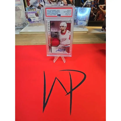 A graded hockey trading card featuring a player in a red jersey with an autograph and a patch.
